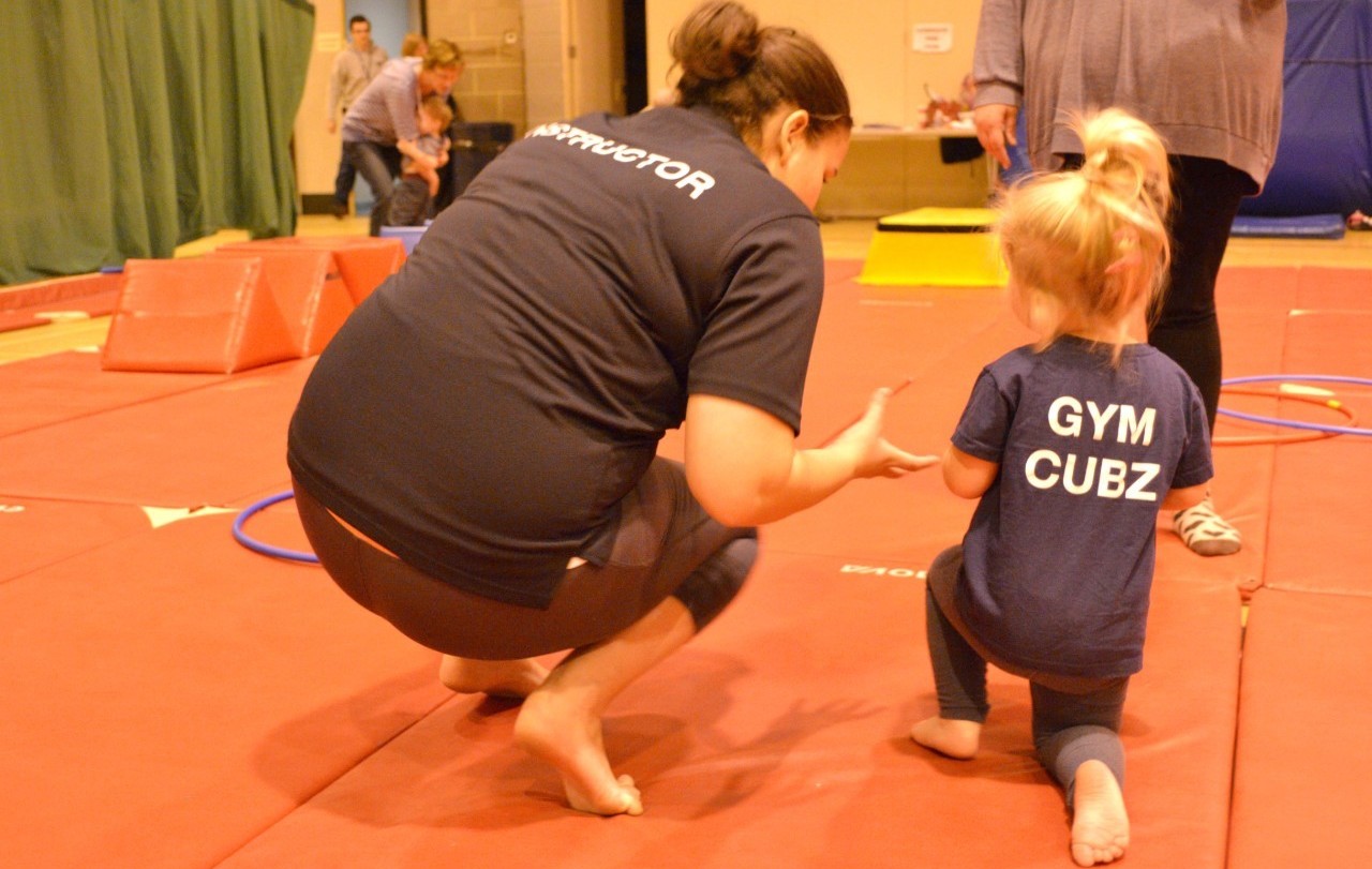 Toddler with gymnastics instructor